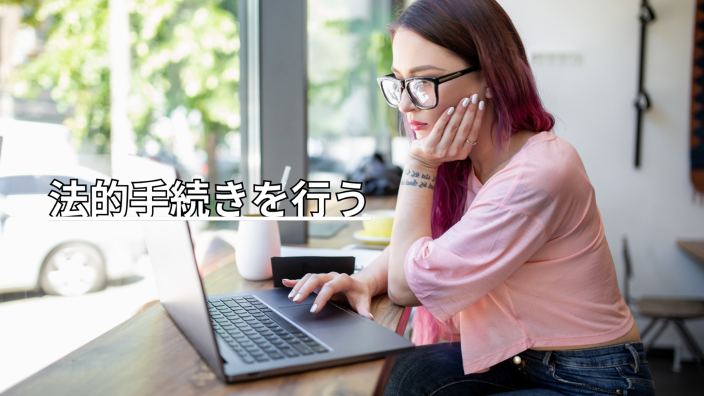 テラス席でパソコン作業を頬杖をつきながら行う黒縁メガネのピンクのロングヘアの女性