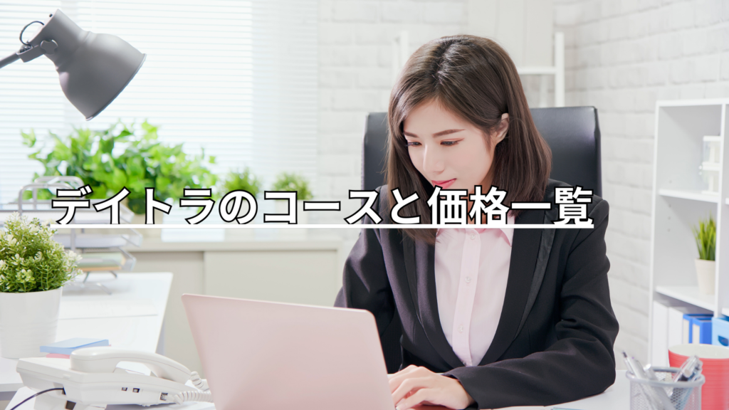 明るくて白い部屋で、パソコンの横に電話をおきながら作業する女性